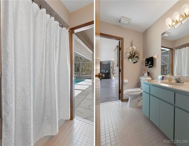 bathroom with tile patterned flooring, toilet, vanity, and a healthy amount of sunlight