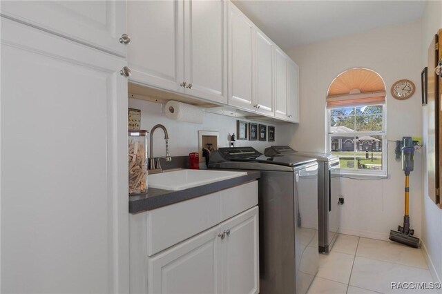 laundry area featuring light tile patterned floors, baseboards, cabinet space, a sink, and independent washer and dryer