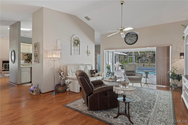 living room with visible vents, high vaulted ceiling, a ceiling fan, wood finished floors, and baseboards