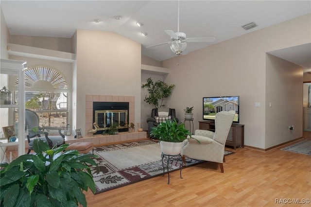 living room featuring a ceiling fan, baseboards, wood finished floors, visible vents, and a fireplace