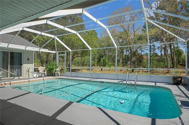 outdoor pool featuring glass enclosure and a patio