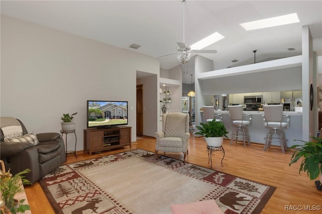 living area with visible vents, high vaulted ceiling, a ceiling fan, wood finished floors, and a skylight