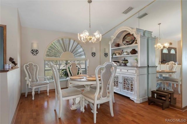 dining space featuring lofted ceiling, a notable chandelier, wood finished floors, and visible vents