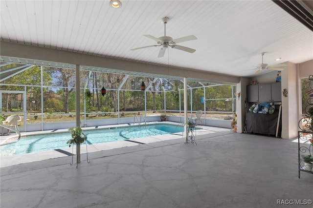 pool with glass enclosure, ceiling fan, and a patio area