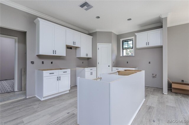 5898 N Flagstaff Ave, Beverly Hills, FL 34465 - kitchen featuring a center island with sink, crown molding, light wood finished floors, and white cabinetry