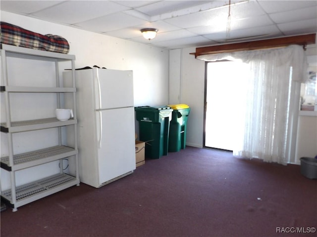 miscellaneous room with a paneled ceiling and dark carpet