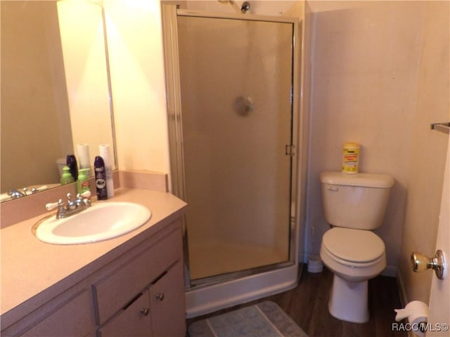 full bath with a stall shower, vanity, toilet, and wood finished floors