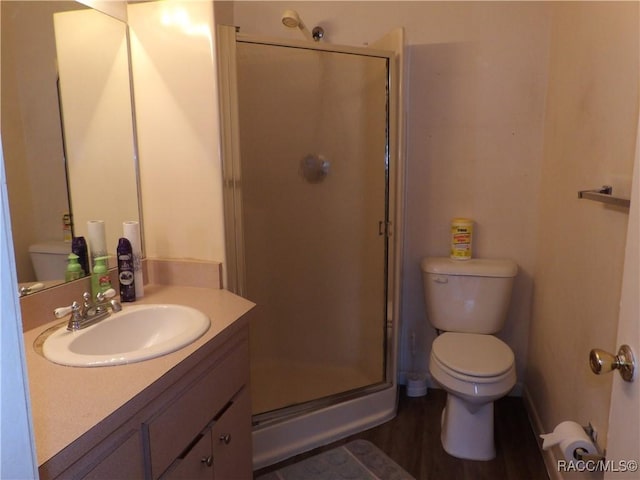 full bathroom featuring toilet, a stall shower, wood finished floors, and vanity