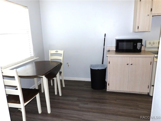 dining space featuring dark wood-style flooring and baseboards