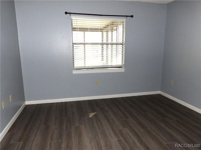 empty room featuring dark wood-style floors and baseboards