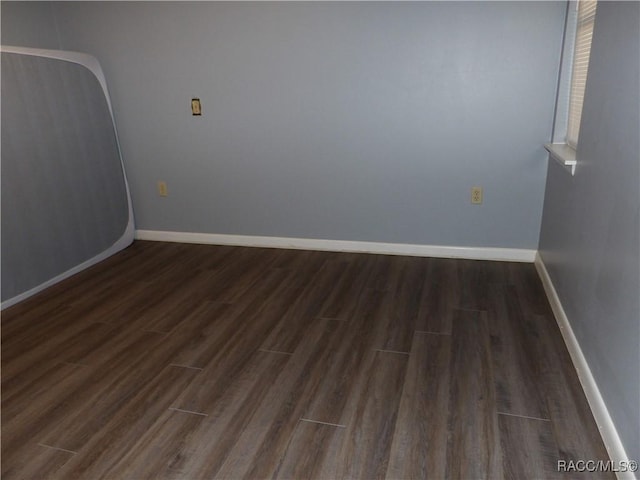 empty room with dark wood-style floors and baseboards