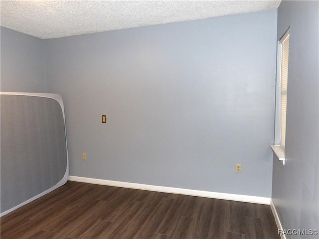 unfurnished room featuring a textured ceiling, dark wood-style flooring, and baseboards