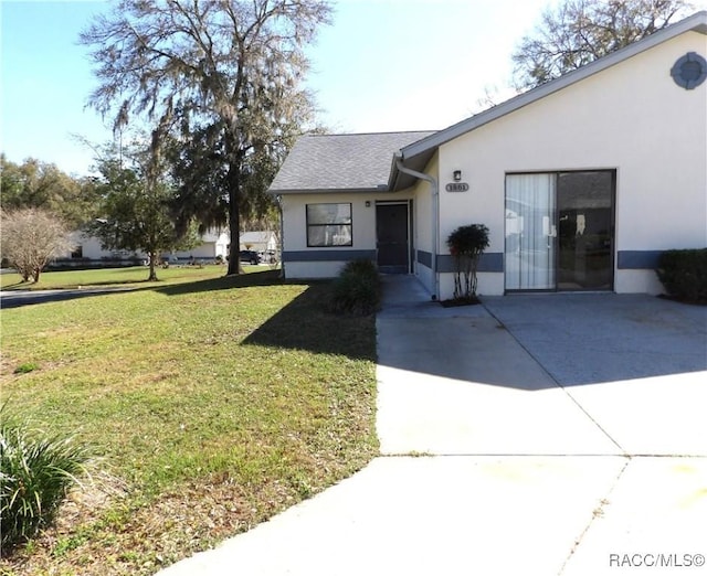 view of front of house featuring a front lawn, concrete driveway, and stucco siding