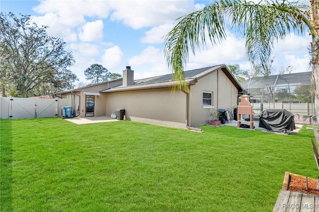 rear view of property featuring a patio area, glass enclosure, and a lawn