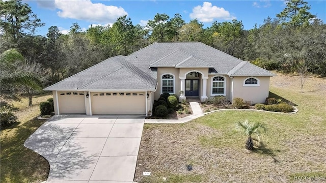 view of front of home featuring an attached garage, driveway, roof with shingles, stucco siding, and a front yard