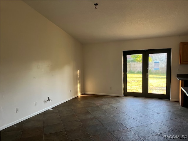 empty room featuring vaulted ceiling, a textured ceiling, and french doors