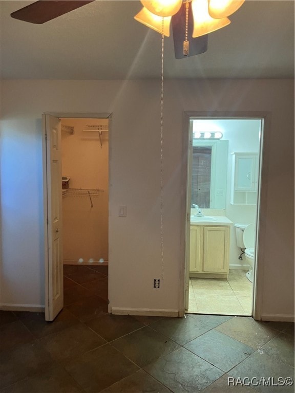 unfurnished bedroom featuring ceiling fan, sink, a spacious closet, connected bathroom, and a closet