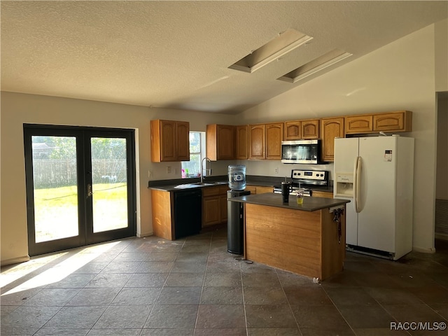 kitchen featuring sink, a textured ceiling, vaulted ceiling, a kitchen island, and appliances with stainless steel finishes