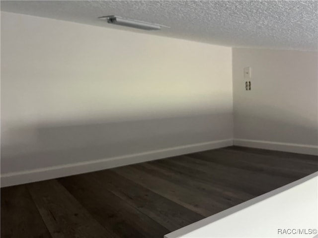 spare room with dark hardwood / wood-style flooring and a textured ceiling