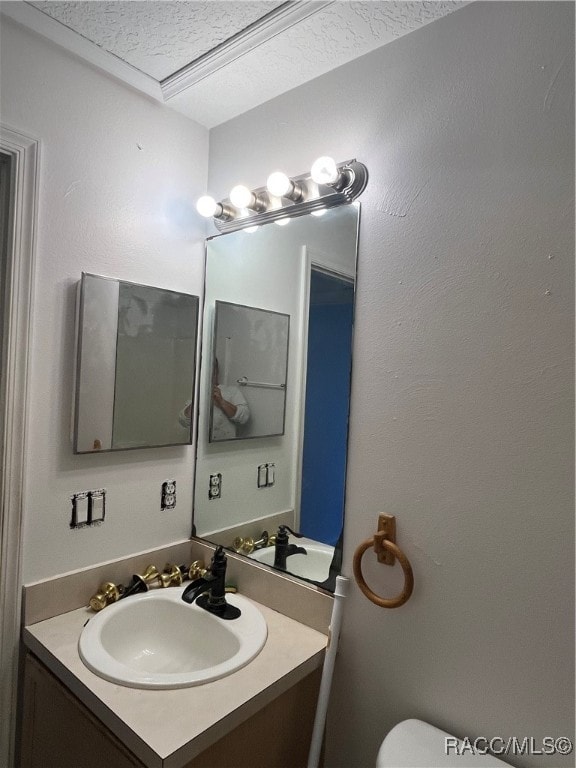 bathroom with vanity, toilet, and a textured ceiling