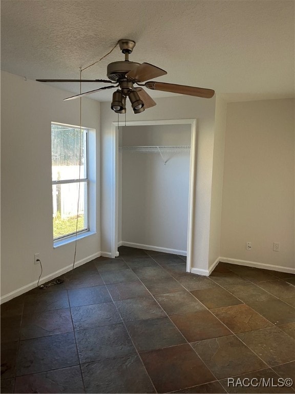 unfurnished bedroom featuring ceiling fan, a textured ceiling, and a closet