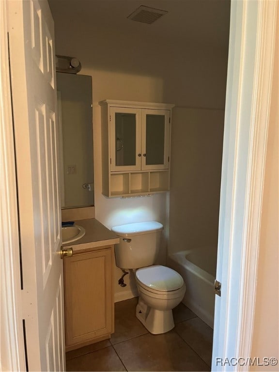 bathroom with tile patterned floors, vanity, a bathtub, and toilet