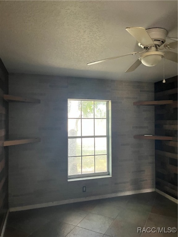 tiled spare room featuring ceiling fan and a textured ceiling