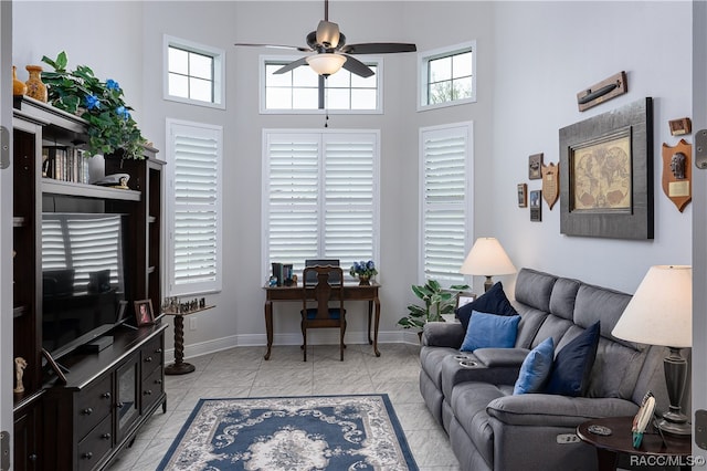 tiled living room with ceiling fan, a healthy amount of sunlight, and a high ceiling