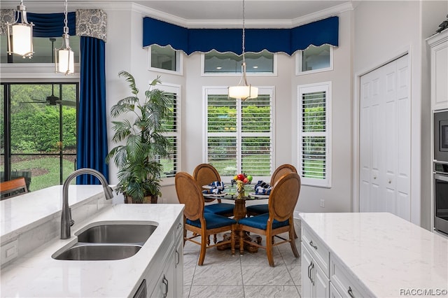 kitchen with a wealth of natural light, white cabinetry, sink, and pendant lighting