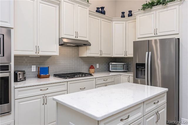 kitchen with backsplash, light stone counters, white cabinetry, and stainless steel appliances