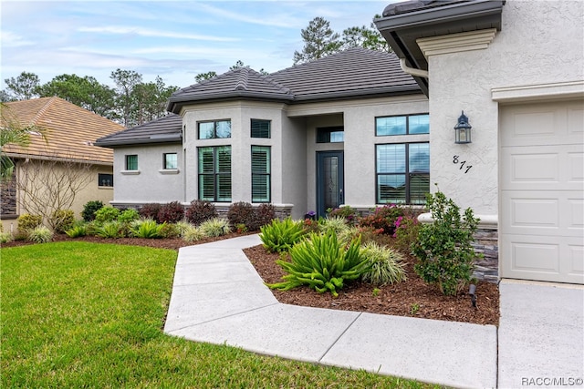 property entrance with a lawn and a garage