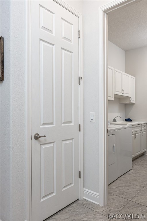 clothes washing area featuring cabinets and a textured ceiling