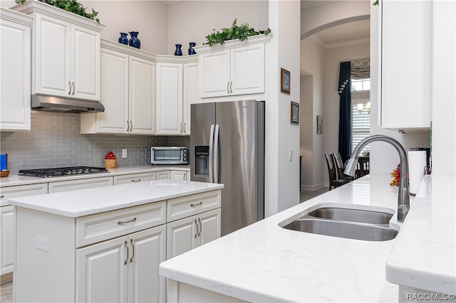 kitchen with white cabinets, appliances with stainless steel finishes, light stone counters, and sink