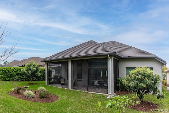 back of property featuring a patio, a lawn, and a sunroom