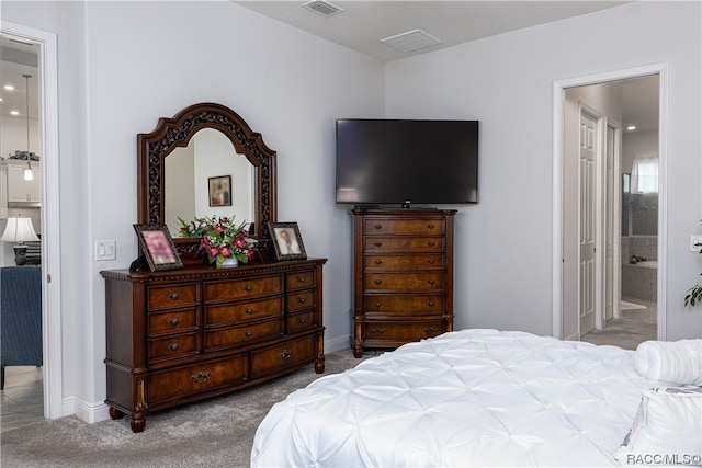 bedroom with ensuite bathroom and light carpet