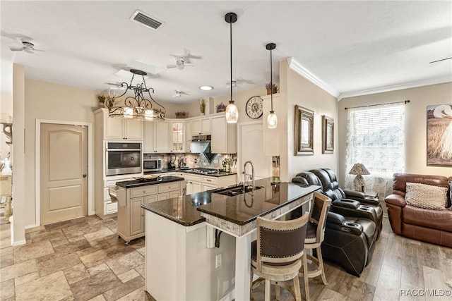 kitchen featuring visible vents, dark countertops, open floor plan, a sink, and stainless steel appliances