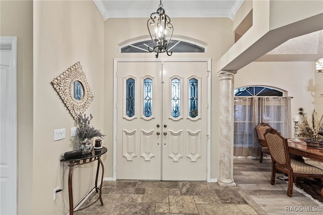 foyer featuring stone finish flooring, baseboards, an inviting chandelier, ornamental molding, and ornate columns