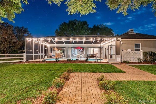 back of property with a yard, a lanai, and an outdoor pool