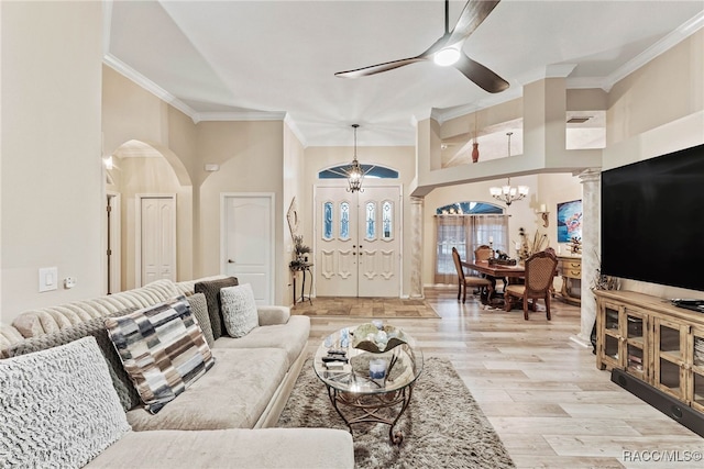 living area featuring arched walkways, ornamental molding, ceiling fan with notable chandelier, and light wood-style flooring