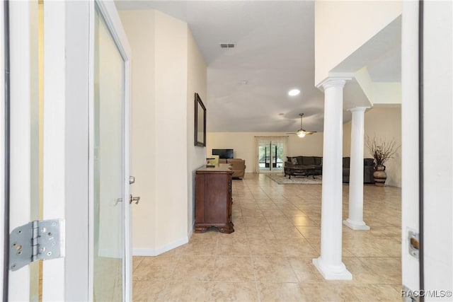 corridor with lofted ceiling, light tile patterned floors, and ornate columns