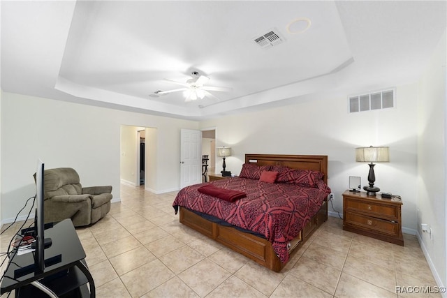 tiled bedroom with ceiling fan and a tray ceiling