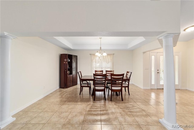 tiled dining room with a tray ceiling, a chandelier, and ornate columns