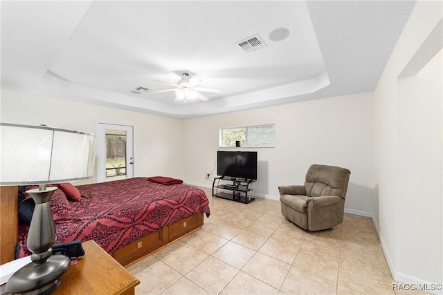 tiled bedroom featuring ceiling fan and a tray ceiling