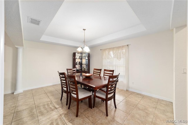 dining space with a raised ceiling, decorative columns, and light tile patterned floors