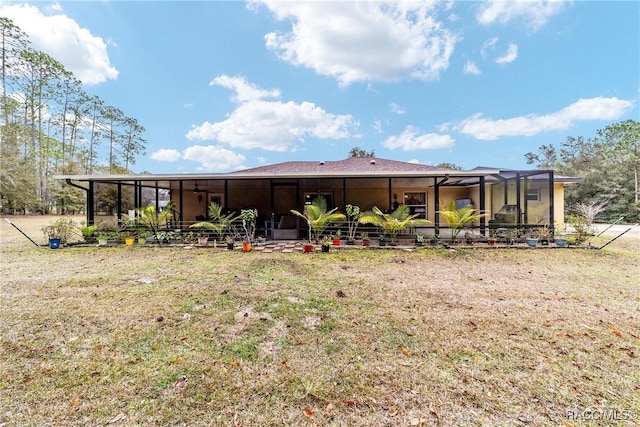 rear view of property featuring a yard and glass enclosure