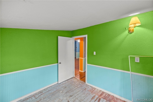 spare room with hardwood / wood-style floors and lofted ceiling