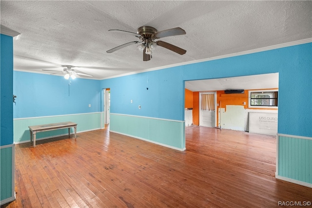 empty room featuring ceiling fan, ornamental molding, a textured ceiling, and hardwood / wood-style flooring