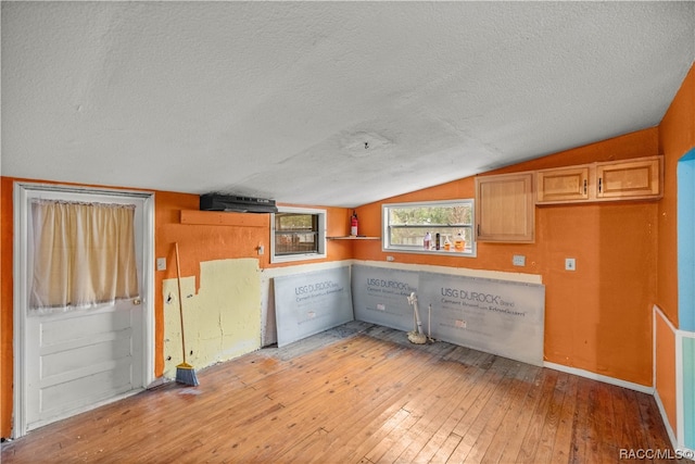 kitchen featuring light hardwood / wood-style floors, lofted ceiling, a textured ceiling, and light brown cabinets