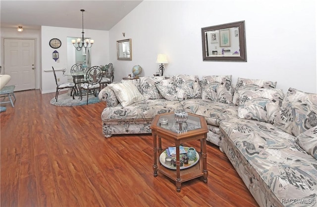 living room featuring vaulted ceiling, dark wood-type flooring, and a chandelier