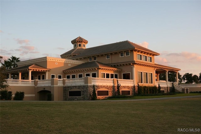 back house at dusk featuring a lawn